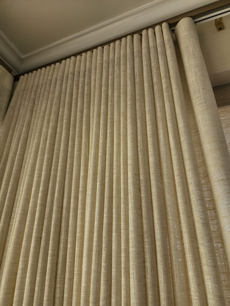 Custom linen drapery with a motorized ripple fold track in a sunlit room.