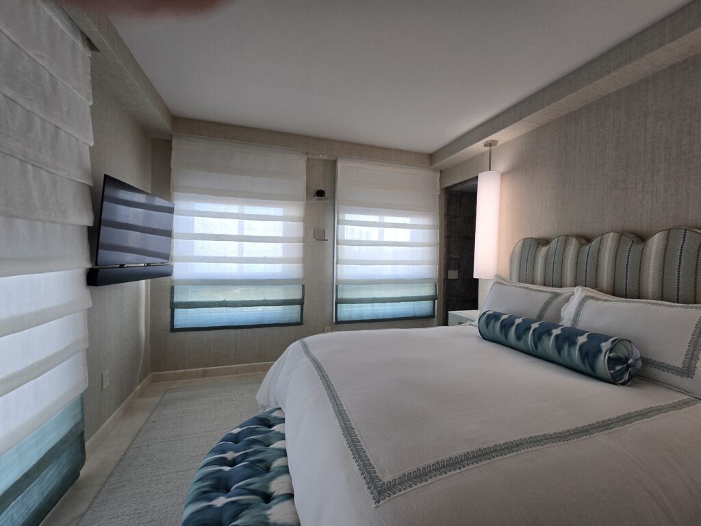 Luxury bedroom suite featuring custom motorized Roman shades, bespoke bedding, and decorative pillows by Magy Interiors for LMD.