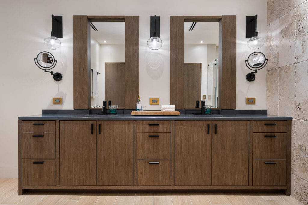 Bespoke bathroom remodel featuring custom-built wood cabinetry crafted to exact dimensions, concealed medicine cabinets, and twin lighted mirrors.
