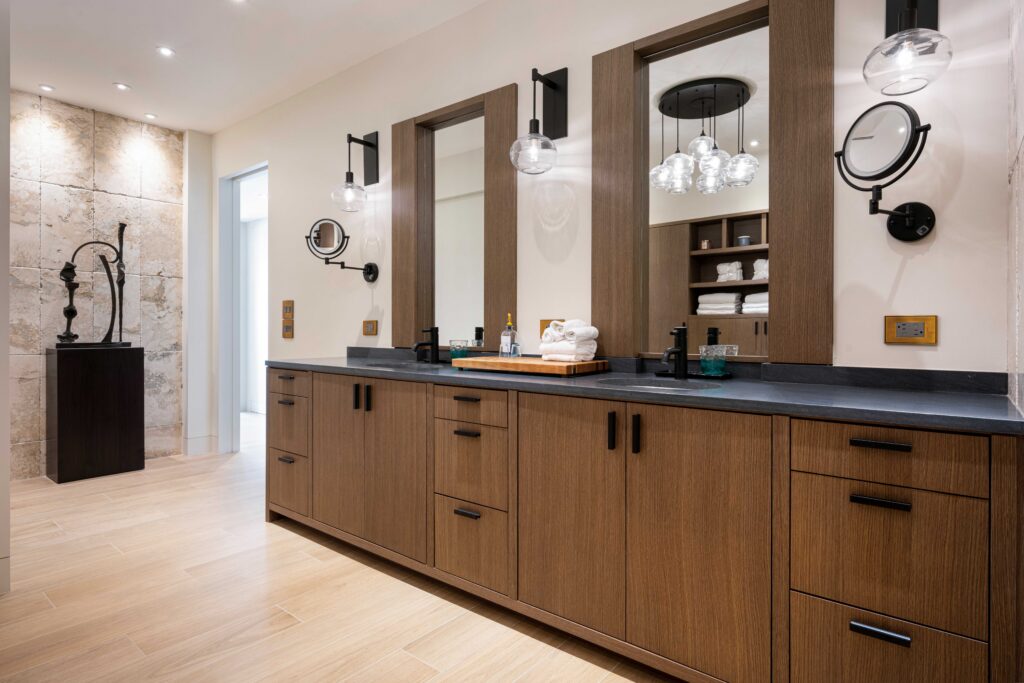 Luxury primary bathroom with custom wood vanity and integrated mirrors by Magy Interiors