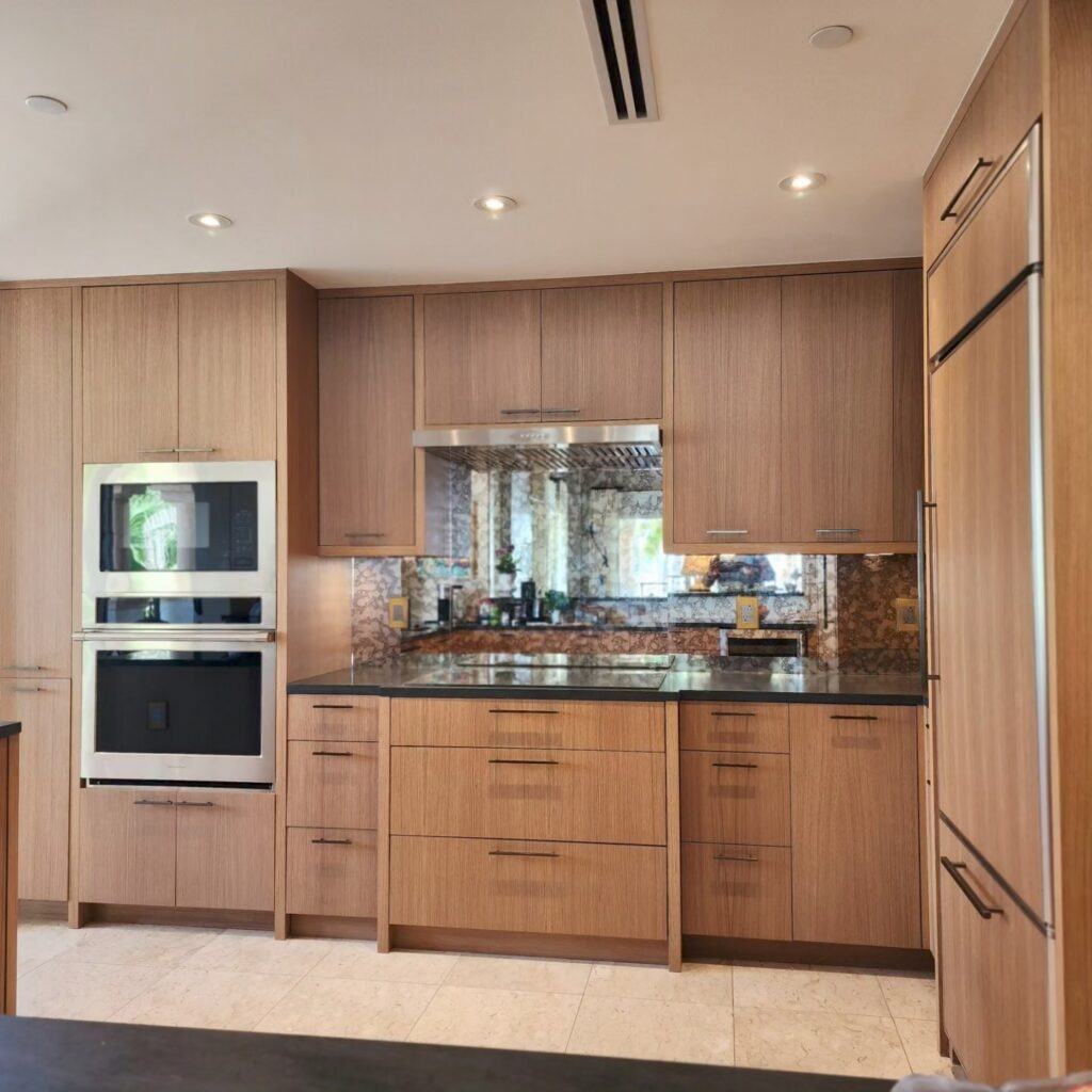 Modern kitchen design with light wood cabinets, gold hardware, and an aged mirror backsplash.