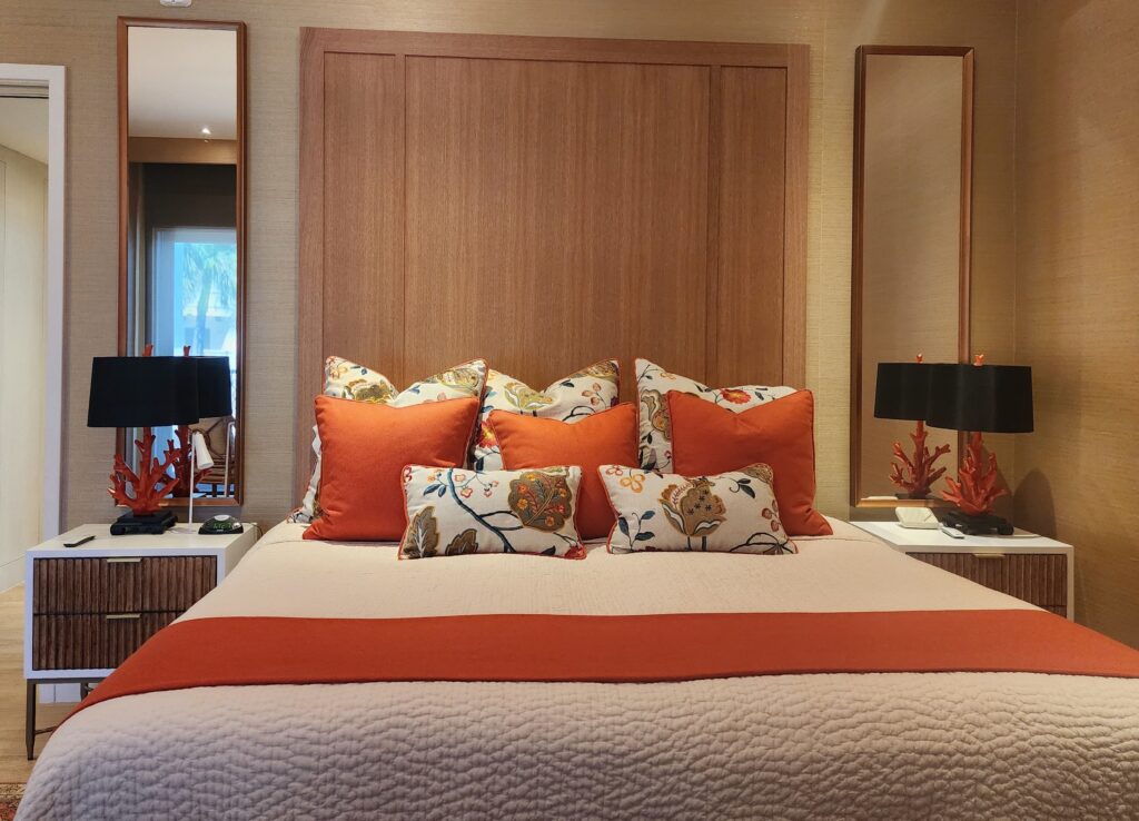 Fisher Island primary bedroom featuring a custom bed, wood-paneled wall, and terracotta accent pillows.