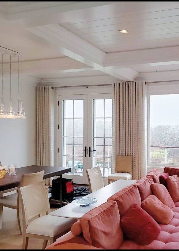 Floor-to-ceiling custom grommets heading draperies and sheer window fashion in a sunlit space.