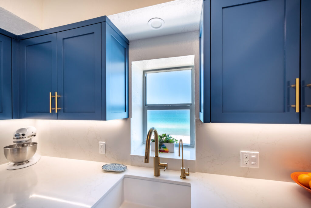 Custom blue kitchen cabinetry and marble backsplash in South Beach condo by Magy Interiors