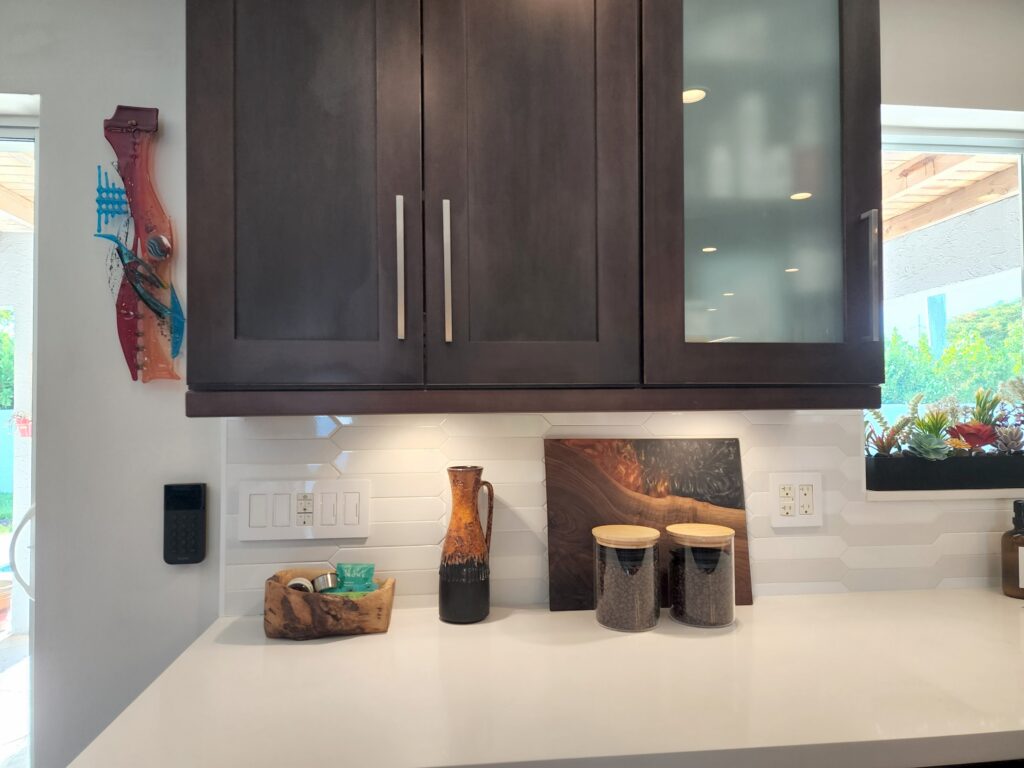 Custom dark wood kitchen cabinetry with under-cabinet lighting and tiled backsplash by Magy Interiors